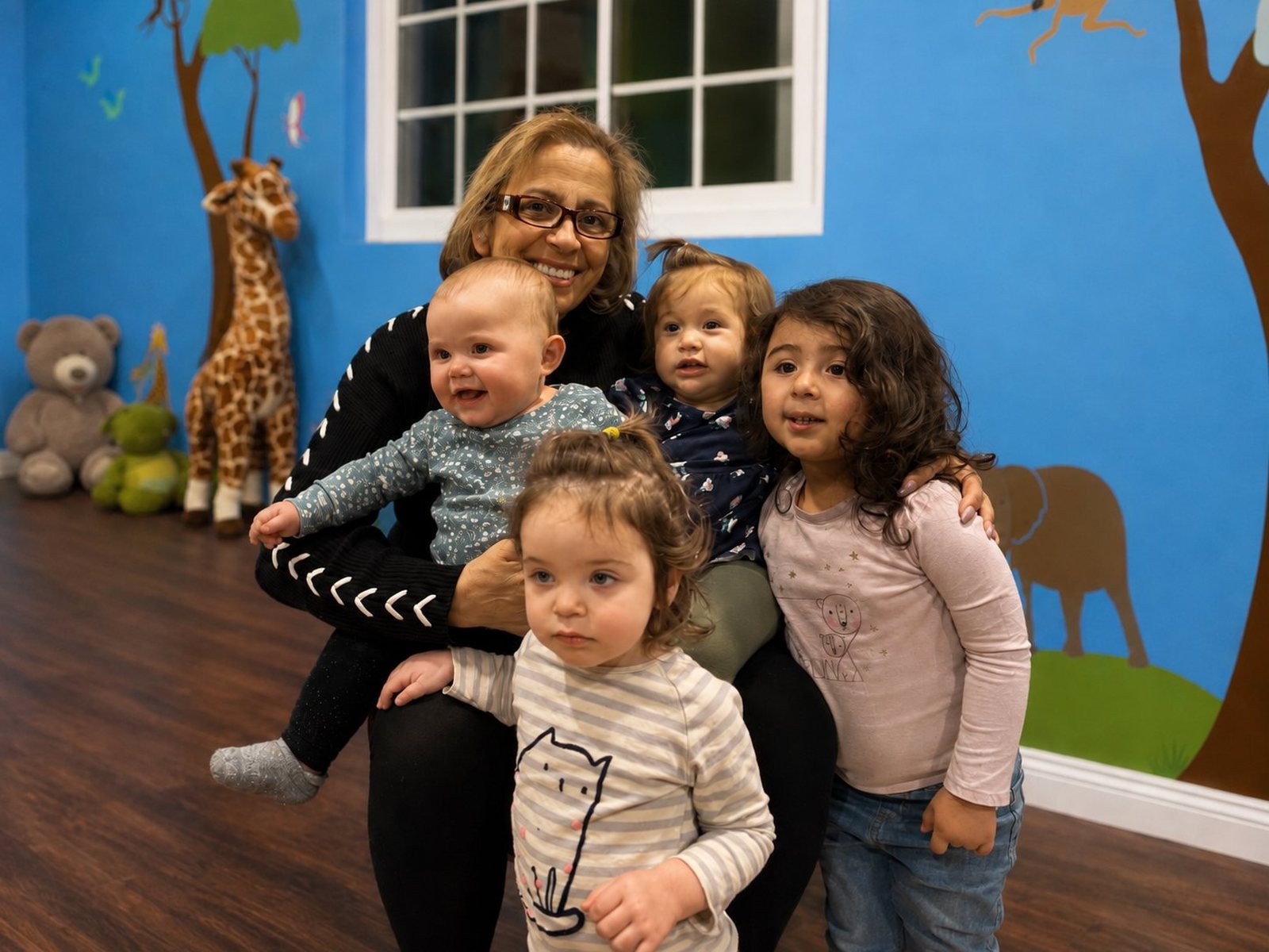 Shila smiling with four children inside her Reseda family daycare.